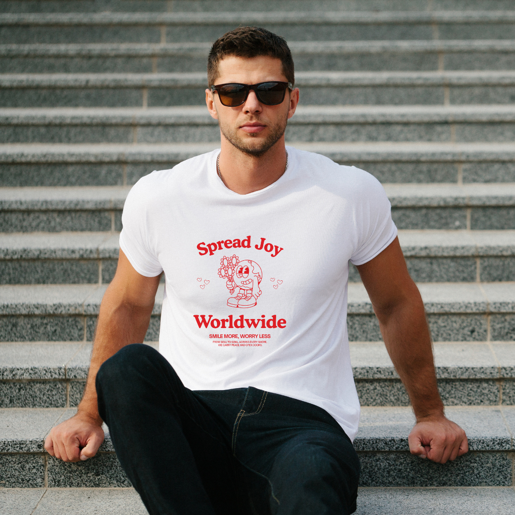 Man wearing a white t-shirt with 'Spread Joy Worldwide' text sitting on steps.