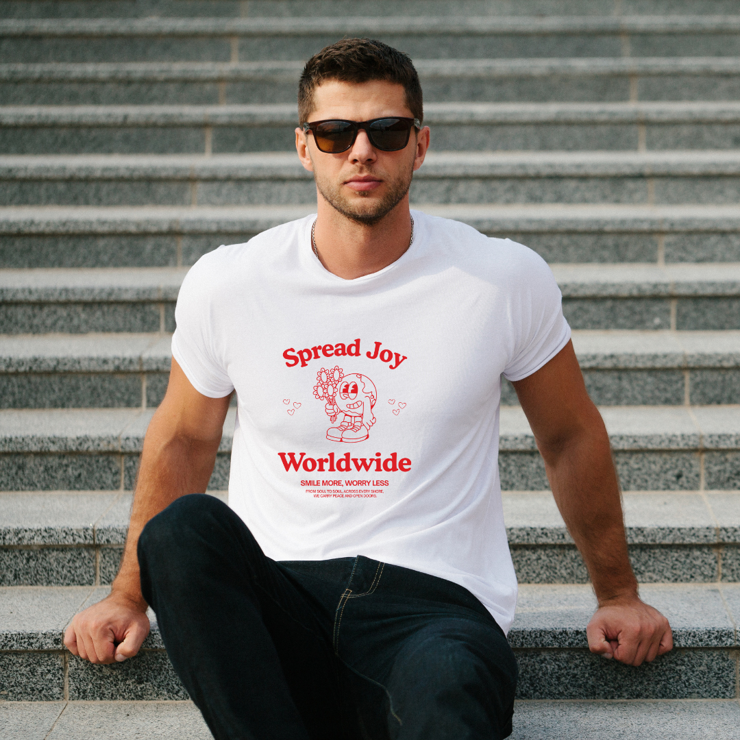 Man wearing a white t-shirt with 'Spread Joy Worldwide' text sitting on steps.